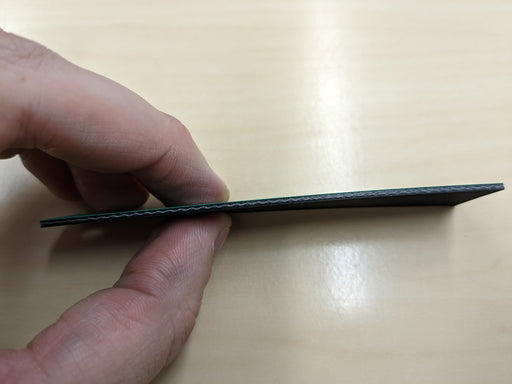 Side view of NC conveyor belt showing 1mm thickness, green diamond surfacing top, and black smooth bottom.