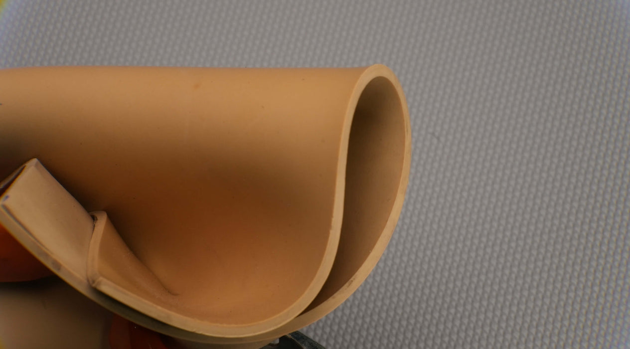 Photo showing flexibility and materials of both sides of Puregum tan rubber with 1/8 inch thickness, tan color, 40 durometer, 3000 psi tensile strength, and 700% elongation.