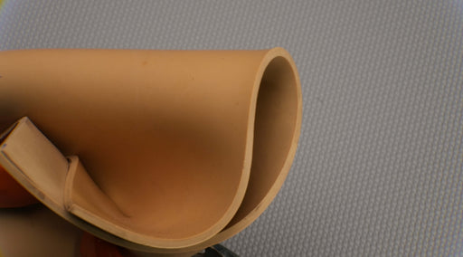 Photo showing flexibility and materials of both sides of Puregum tan rubber with 1/8 inch thickness, tan color, 40 durometer, 3000 psi tensile strength, and 700% elongation.