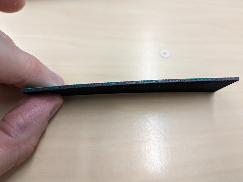 Side view of NC conveyor belt showing 1.4mm thickness, green diamond surfacing top, and black smooth bottom